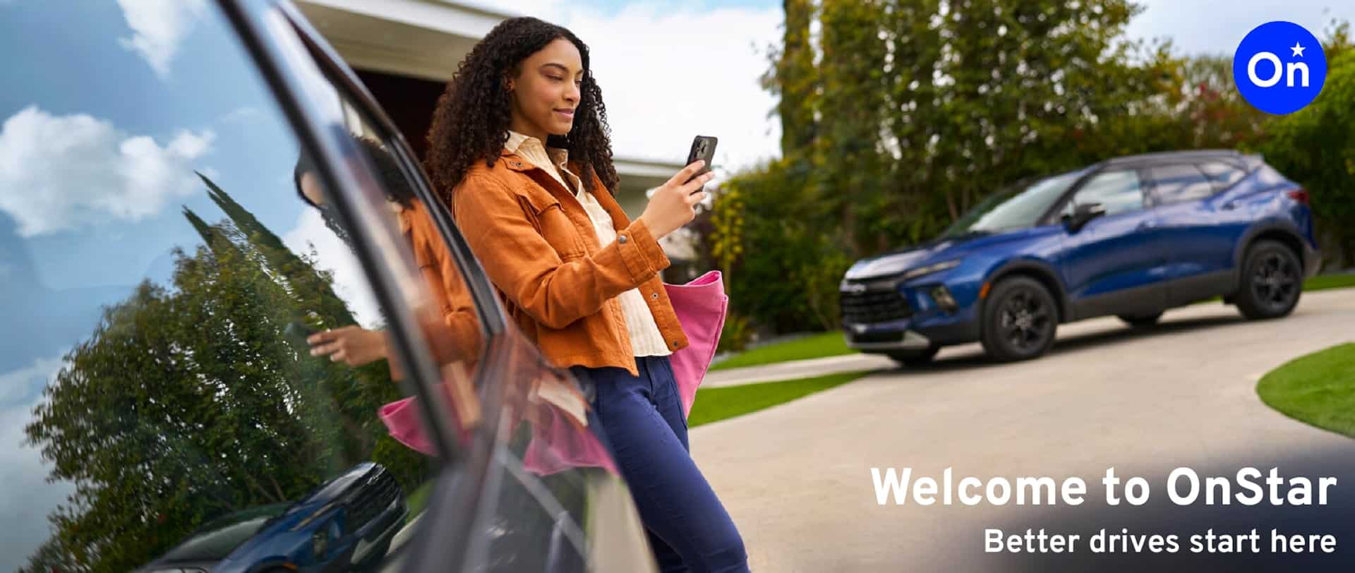 Woman using smartphone near car, with a blue SUV parked on driveway. OnStar logo and slogan in view.