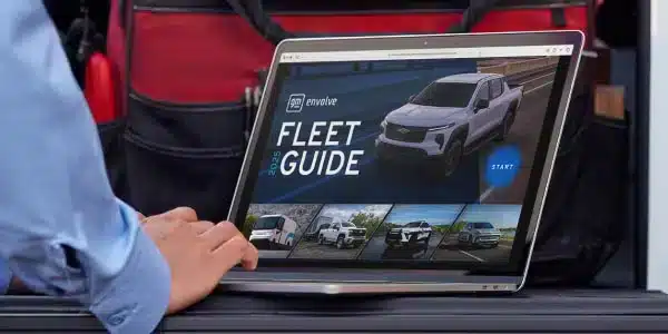 Person viewing a laptop screen displaying the 2024 Fleet Guide featuring a white vehicle and start button.