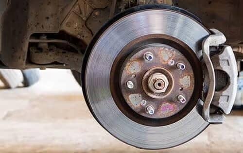 Close-up of a car's brake disc and caliper, showing rust and wear on the metal surface.