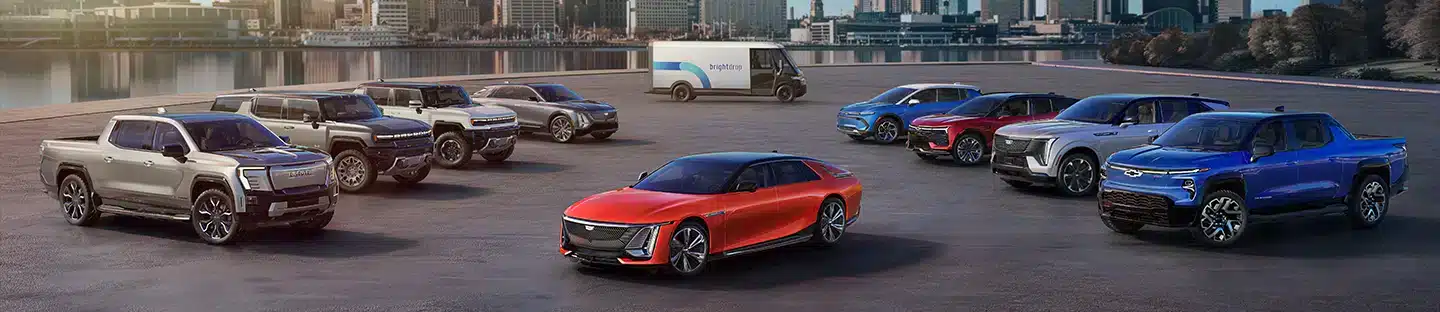 Assorted electric vehicles displayed in front of a cityscape, featuring trucks and a bright van.