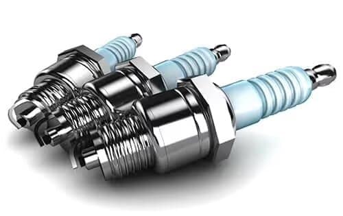 Three metallic spark plugs aligned, showcasing their threaded bodies and ceramic insulators.