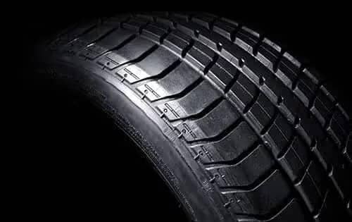 Close-up of a car tire tread with a geometric pattern, highlighting grip and durability.