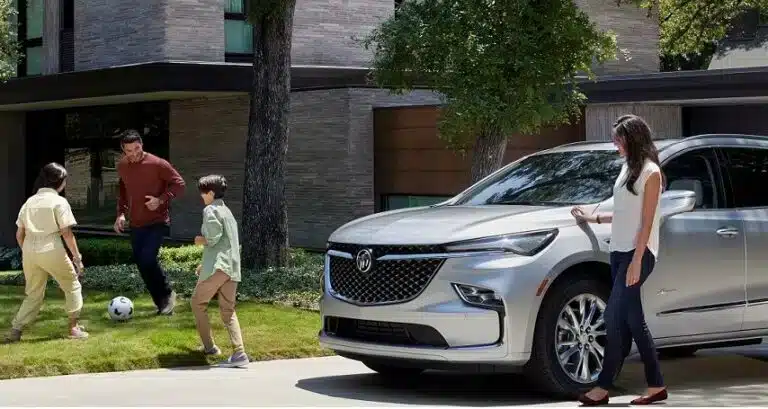 Family playing soccer near a modern SUV, parked in front of a contemporary house.