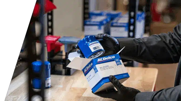 Person holding an ACDelco oil filter box on a workbench, with more filters in the background.