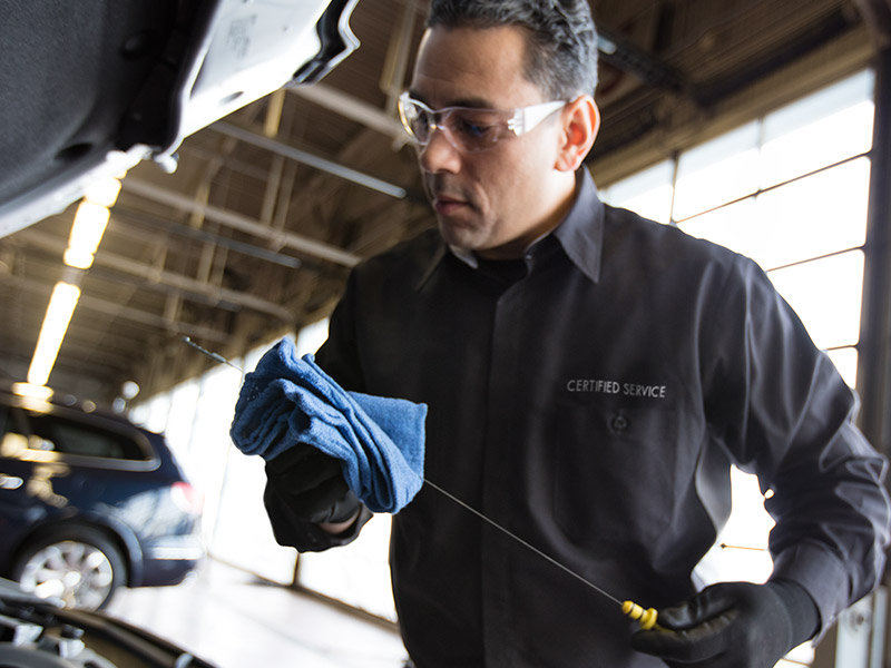 A Chevrolet Certified Service technician checking a vehicle's oil