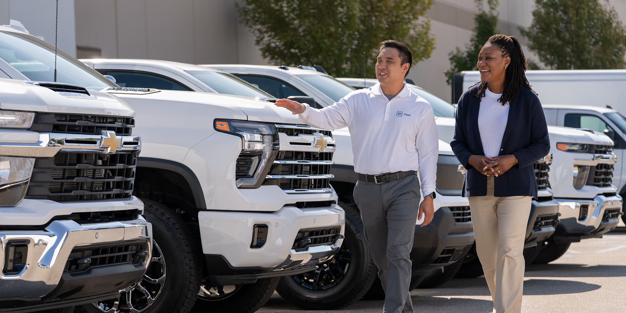 A member of the RMP Chevrolet team walking a customer along a row of Chevrolet trucks