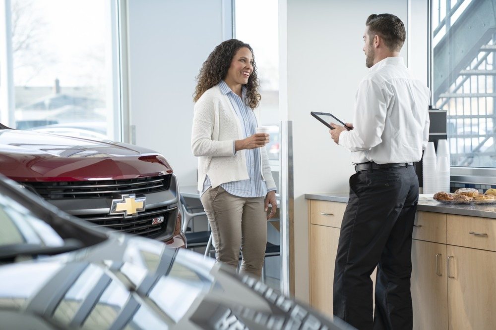 A customer and a sales consultant talking in the lounge beside a Chevrolet Colorado