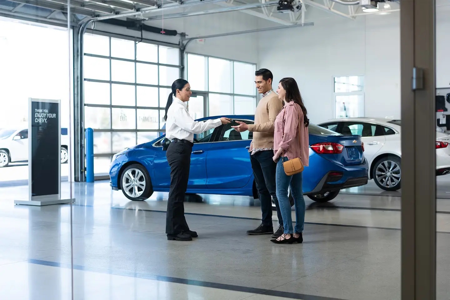 Keys being handed to a couple beside their new Chevrolet